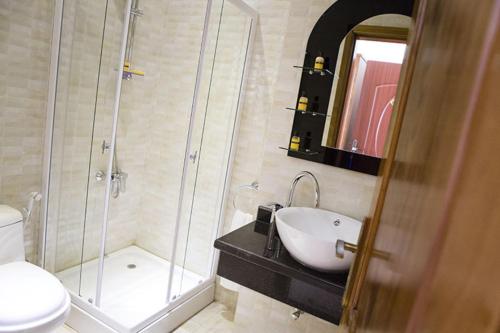 a bathroom with a sink and a shower and a toilet at Hotel Bella Riva Kinshasa in Kinshasa