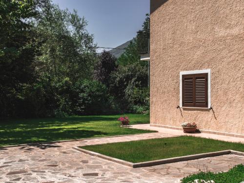 a building with a window on the side of a yard at Alloggio del Fiume - Le Vecchie Vasche in Scoppito