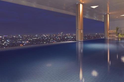 a swimming pool with a view of a city at night at FOX Hotel Pekanbaru in Pekanbaru