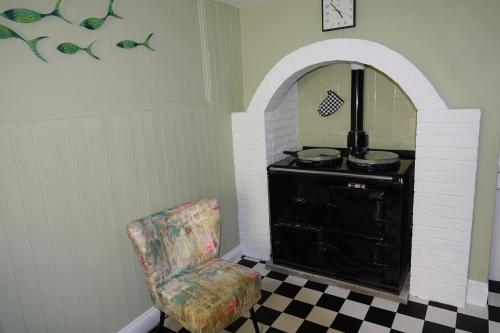 a living room with a chair and a stove at Saffron House in Fowey