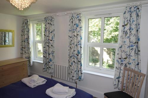 a bedroom with a blue bed and two windows at Saffron House in Fowey