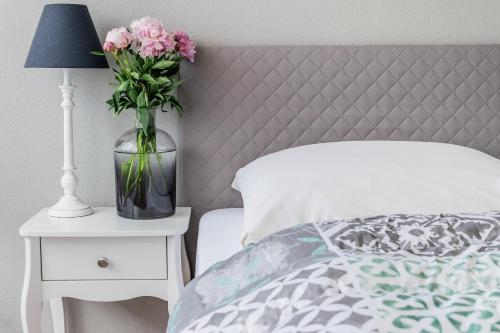 a vase of pink flowers on a night stand next to a bed at Landhotel Stegersbach in Stegersbach
