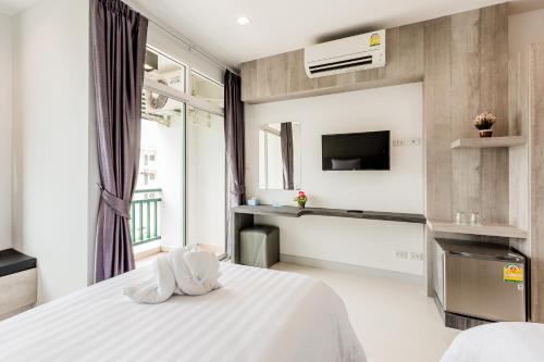 a bedroom with a white bed and a tv at Evergreen Suite Hotel in Suratthani