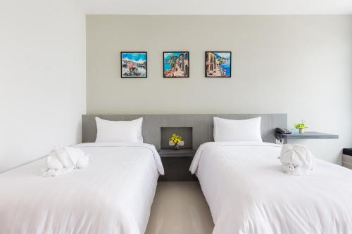 two beds with white sheets with stuffed animals on them at Evergreen Suite Hotel in Surat Thani