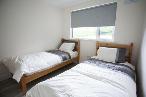 two beds in a small room with a window at Newcastle Court in Galway