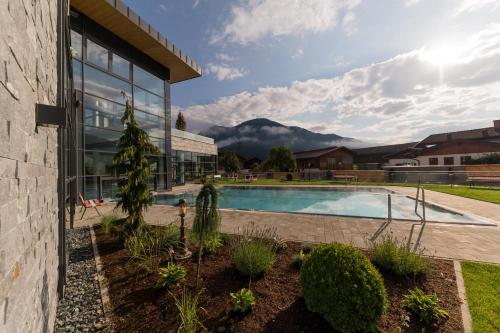 a house with a swimming pool with mountains in the background at Woferlgut - Wellness & Sport in Bruck an der Großglocknerstraße