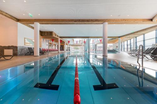 a large swimming pool with a red raft in it at Woferlgut - Wellness & Sport in Bruck an der Großglocknerstraße