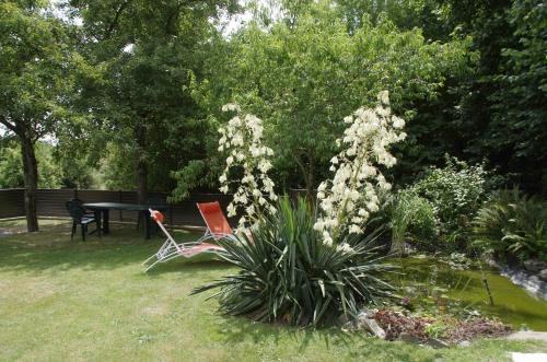 einen Garten mit einem Tisch, Stühlen und Blumen in der Unterkunft La Parquerie in Orval