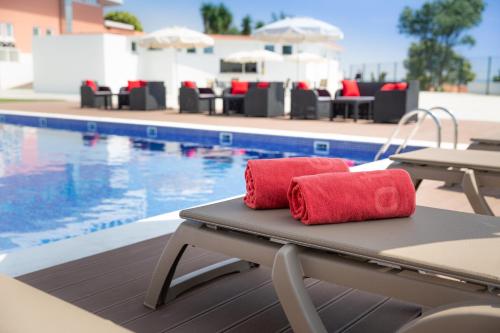 two red towels sitting on a table next to a pool at Luna Hotel Turismo in Abrantes