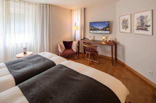 a bedroom with a bed, desk, chair and television at Waldhotel Stuttgart in Stuttgart