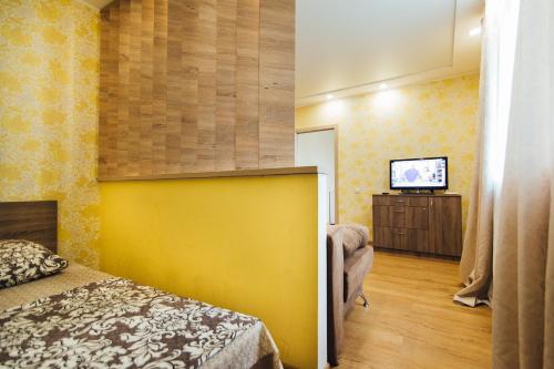 1 dormitorio con pared amarilla y TV en Apartments Faraon, en Sumy