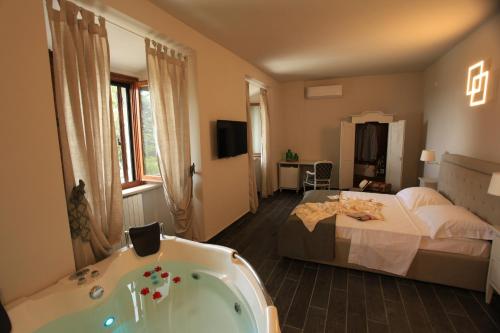 Habitación de hotel con bañera y cama en Hotel Le Macine, en Montaione