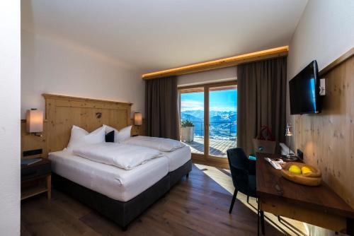 a hotel room with a bed and a desk and a window at BichlAlm Berggasthof in Kitzbühel