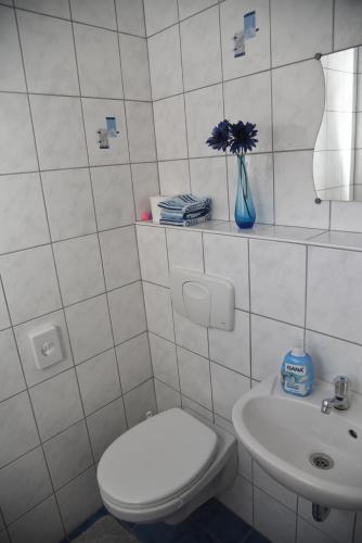 a white tiled bathroom with a toilet and a sink at Pension Heib in Cochem