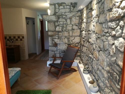 a chair in a room with a stone wall at Holiday Farmhouse Skvor in Robidišče