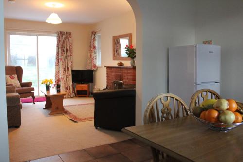 uma sala de estar com uma mesa e um frigorífico em Giant's Causeway Holiday Cottages em Bushmills