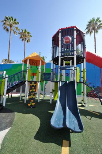 a playground with a slide in a park with palm trees at Spring Hotel Bitácora in Playa de las Americas