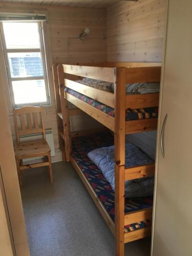 Vejers Family Camping & Cottages في فايرس ستراند: غرفة بسريرين بطابقين وكرسي