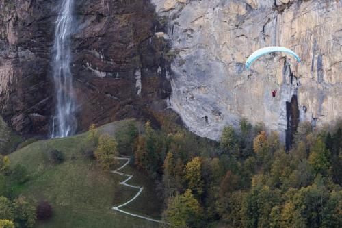 a person flying a parachute over a waterfall at O 68 Haus Bel Air in Wengen