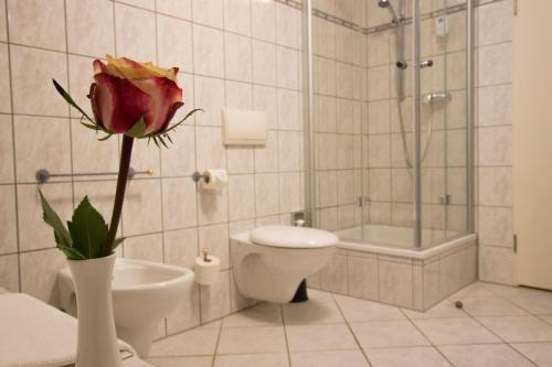 a bathroom with a toilet and a flower in a vase at Hotel am Luisenplatz in Potsdam