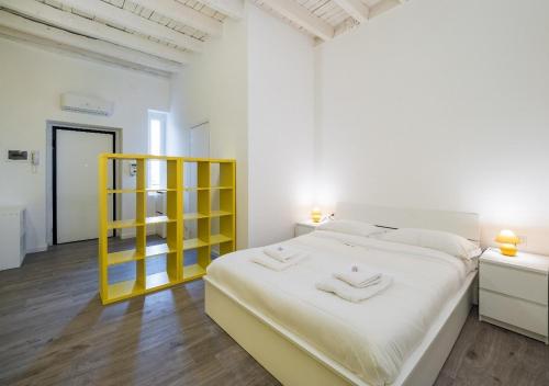 Dormitorio blanco con cama amarilla y estante amarillo en Central Station Apartment, en Milán