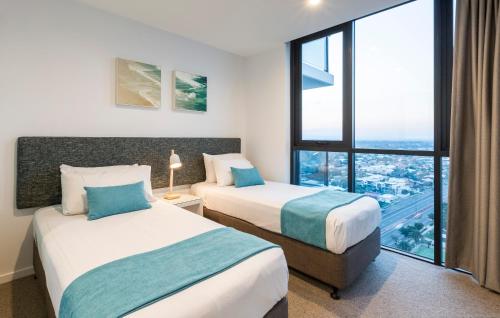 two beds in a hotel room with a large window at Boardwalk Burleigh Beach - Official in Gold Coast