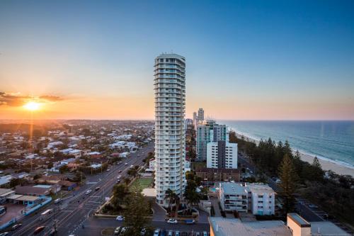 a tall building in front of a city with the ocean at Boardwalk Burleigh Beach - Official in Gold Coast