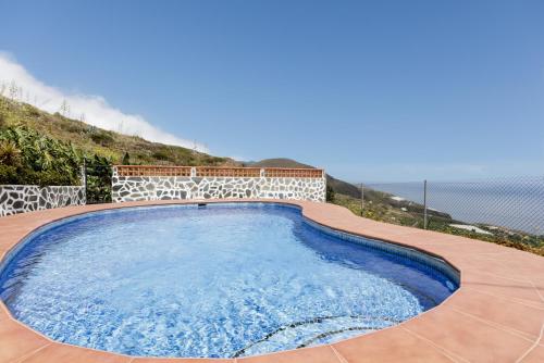a swimming pool on a patio with the ocean in the background at Tomasín in Puntallana
