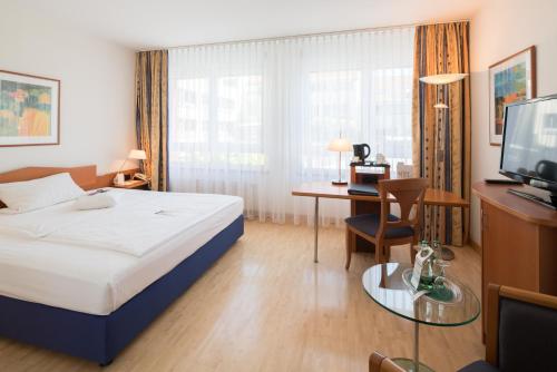 a hotel room with a bed and a desk and a television at Best Western Hotel Am Straßberger Tor in Plauen