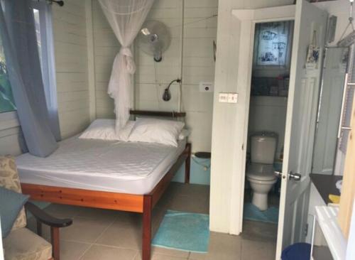 a small bedroom with a bed and a toilet at Cosy Hut in Saint Georgeʼs