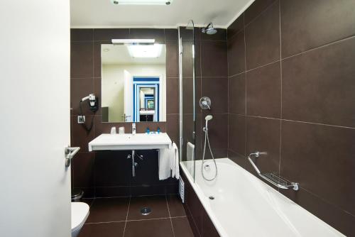een badkamer met een bad, een wastafel en een spiegel bij RR Alvor Baía Resort in Alvor