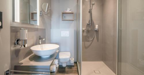 a bathroom with a sink and a toilet and a shower at Hotel zur Post - Economy Rooms in Garrel