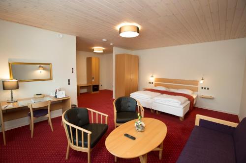 um quarto de hotel com uma cama, uma mesa e cadeiras em Agerskov Kro & Hotel em Agerskov