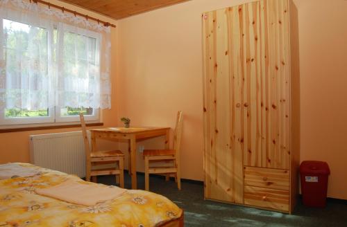 a bedroom with a bed and a table and a window at Pension Pod Hrádečkem in Höllenhäuser