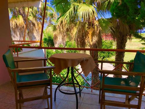a table and chairs on a balcony with palm trees at Ionos in Pyrgi Thermis
