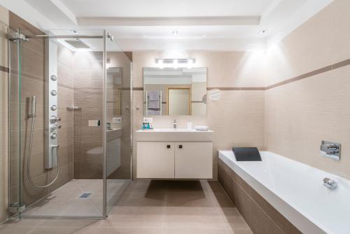 a bathroom with a shower and a sink and a tub at Avita - suites to relax in Ortisei