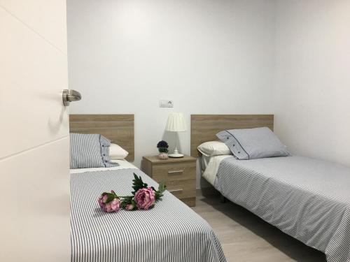 two beds in a room with flowers on the beds at Castro Sun And Beach in Castro-Urdiales