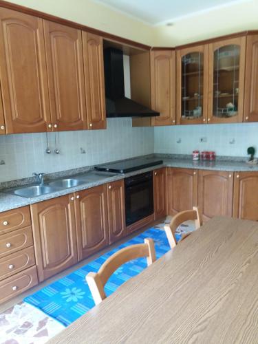 una cocina con armarios de madera y una mesa con sillas. en B&B Misatere, en Vallelonga