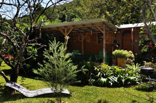 a garden with a house with a bench and plants at West Indies Cottage in Pointe-Noire
