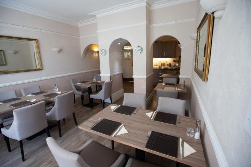 a restaurant with wooden tables and white chairs at Corner House Hotel Gatwick with bookable Holiday parking in Horley