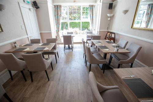 a restaurant with wooden tables and chairs and a window at Corner House Hotel Gatwick with bookable Holiday parking in Horley