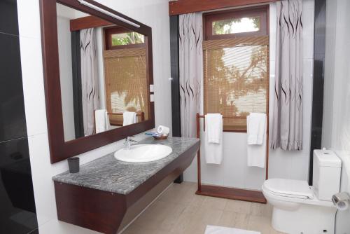 Un baño con lavabo, inodoro y espejo. en Riverside Inn Fuji, en Bentota