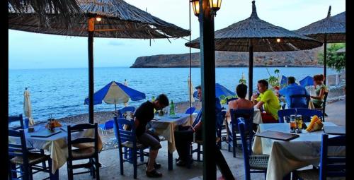 a group of people sitting at tables with umbrellas on the beach at Beachfront Apartment Kato Zakros in Káto Zákros