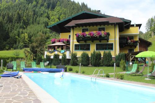 a hotel with a swimming pool in front of a house at Schattaugut in Eben im Pongau