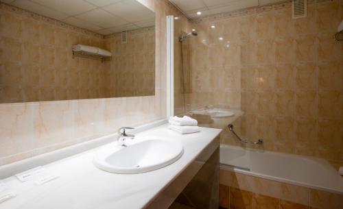 y baño con lavabo, ducha y bañera. en Apartamentos Vértice Bib Rambla, en Sevilla