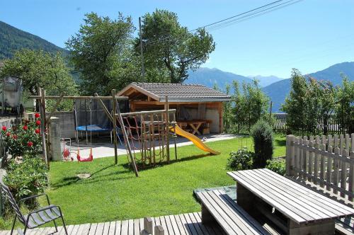 un patio con parque infantil y una casa en Morigglhof en Malles Venosta