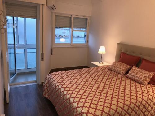 um quarto com uma cama, uma janela e um candeeiro em Rua Conselheiro Bivar em Faro