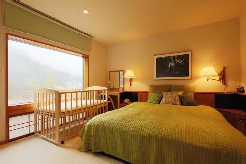 a bedroom with a crib and a bed and a window at Condominium Sakura in Hakone