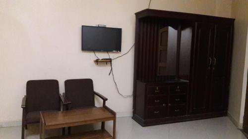 a room with two chairs and a tv on a wall at Saj Rest' inn in Kannur