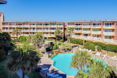 an aerial view of a hotel with a pool and palm trees at The Victorian in Galveston